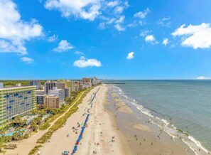 Ein Hotel direkt am Strand mit einem langen, sandigen Strand, Blick auf den Ozean und modernen Gebäuden.