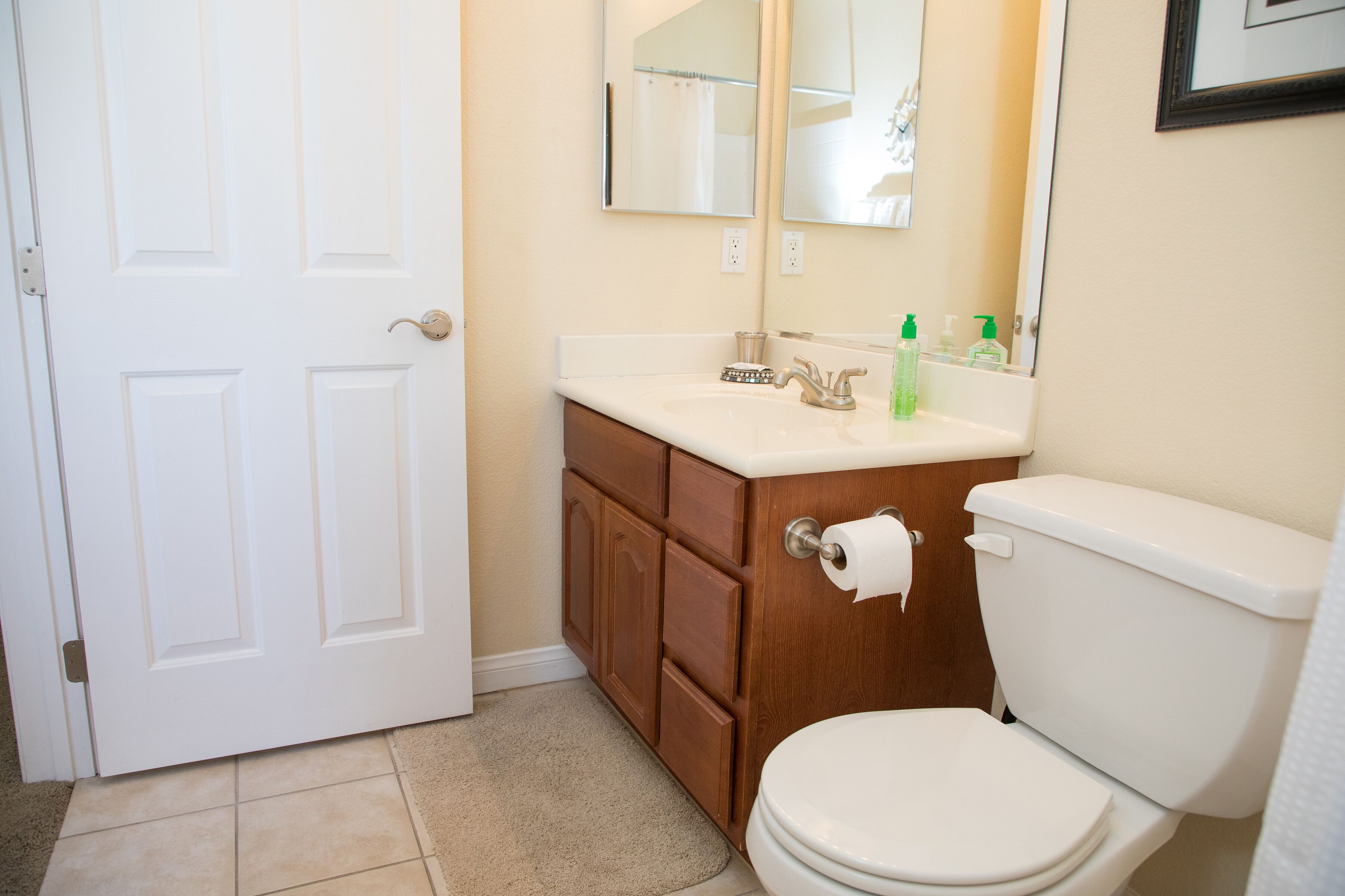 Un bagno con il water bianco, un mobile bagno in legno e uno specchio sopra il lavandino.