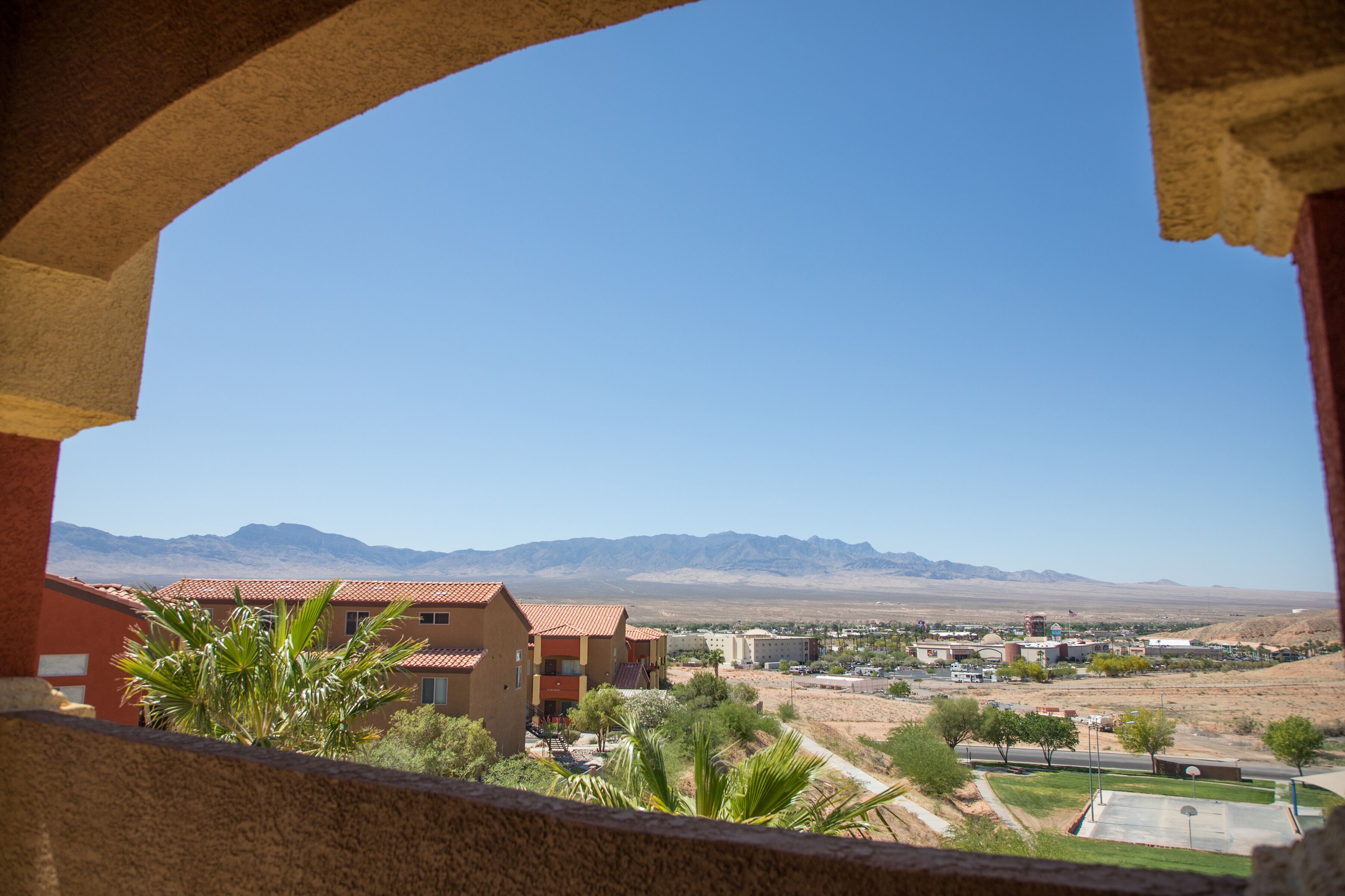 A view from a balcony overlooking a residential area with buildings and mountains in the distance.