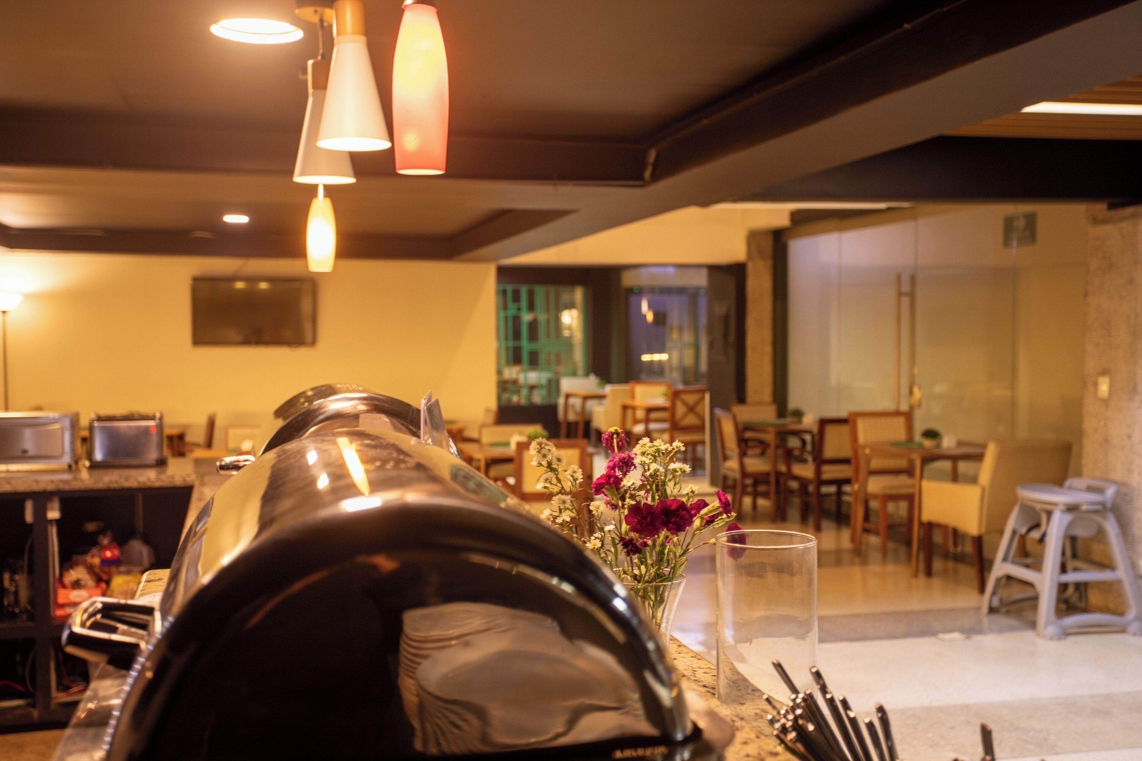 Un coin cuisine avec une machine à café, un verre d’eau et un vase rempli de fleurs.