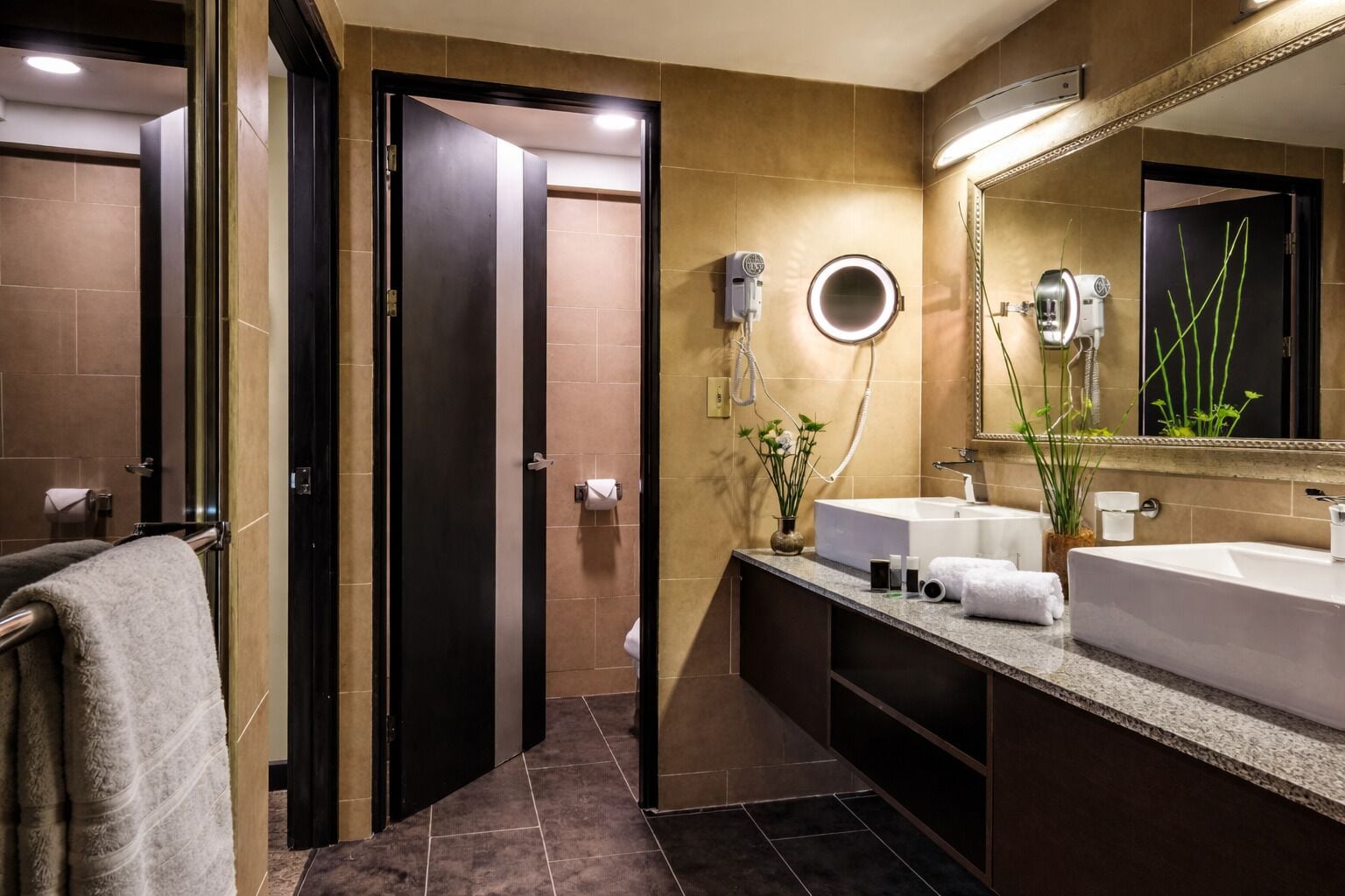 A modern bathroom with two sinks, a large mirror, a hairdryer, and a towel rack.
