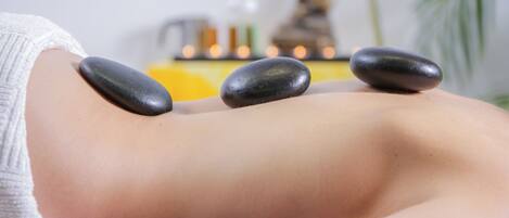 A massage therapy session with stones on a client's back.