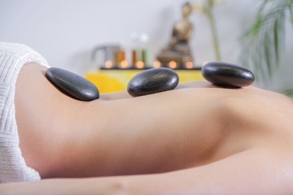 A massage therapy session with stones on a client's back.