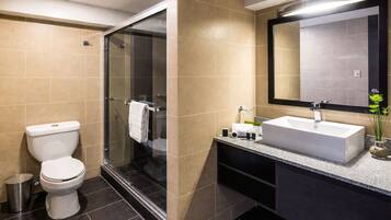 A modern bathroom with a toilet, shower, and sink.