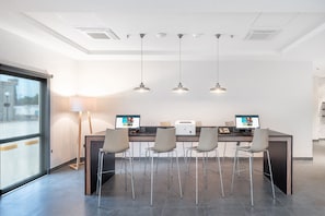 Een moderne kantoorruimte met een lange tafel, vier stoelen, twee monitoren en hanglampen.