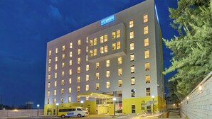 A multi-story hotel with a prominent 'City Express' sign, a covered entrance, and a parking area with a white van.