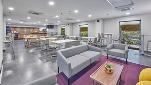 A modern dining area with tables and chairs, a sofa, and a coffee table.