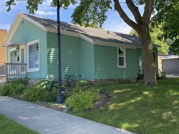 A single-story house with a front porch and a tree in the yard. - Adorable cottage with modern style , we welcome you to your temporary home! (Sturgeon Bay)