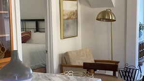 Eine moderne Küche mit Marmorarbeitsplatte, ein Essbereich mit Holzstühlen, eine Stehlampe und ein Gemälde an der Wand.