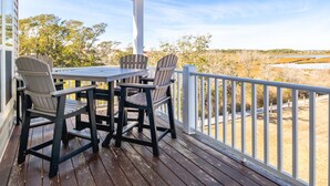 Une terrasse en bois avec une table et des chaises, offrant une vue sur un paysage naturel.