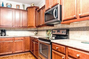 A kitchen with wooden cabinets, a microwave, an oven, and a coffee maker.