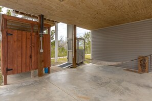 A covered outdoor area with a wooden door, a concrete floor, and a metal gate.