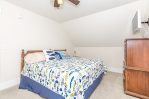 Un dormitorio con cama, mesita de noche, cómoda y ventilador de techo.