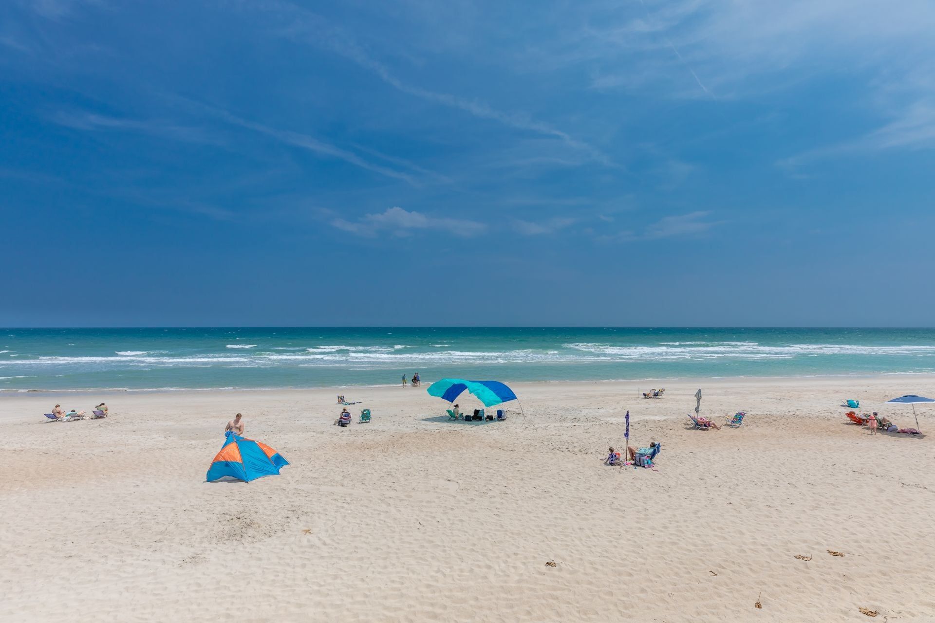 A beach with umbrellas and people.