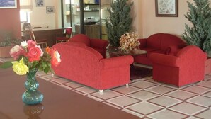 Um hall com sofás vermelhos, uma mesa de centro e um vaso de flores.