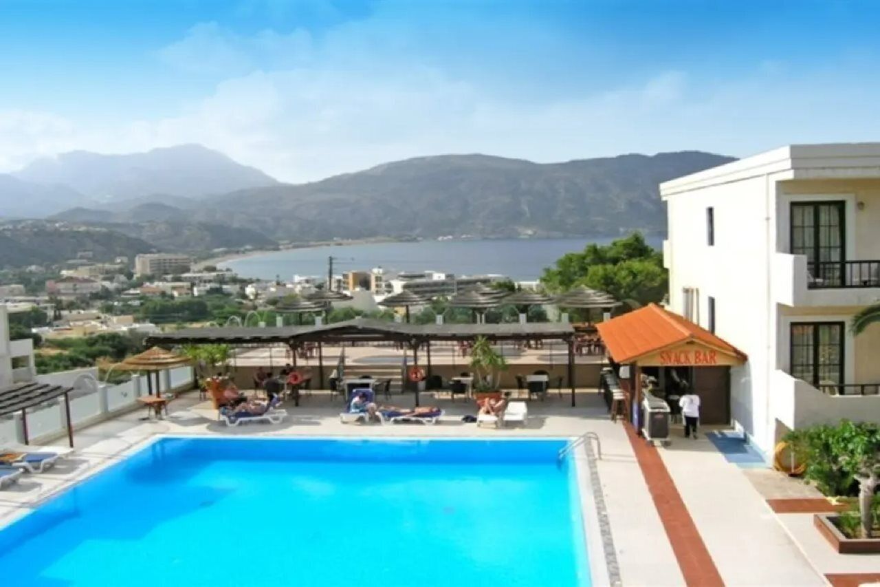 Ein Schwimmbecken mit Liegestühlen und Sonnenschirmen, eine Snackbar und Blick auf die umliegende Landschaft.