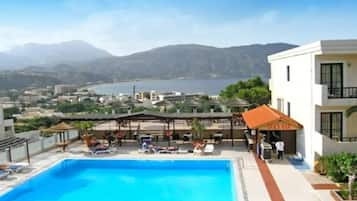 Ein Schwimmbecken mit Liegestühlen und Sonnenschirmen, eine Snackbar und Blick auf die umliegende Landschaft.