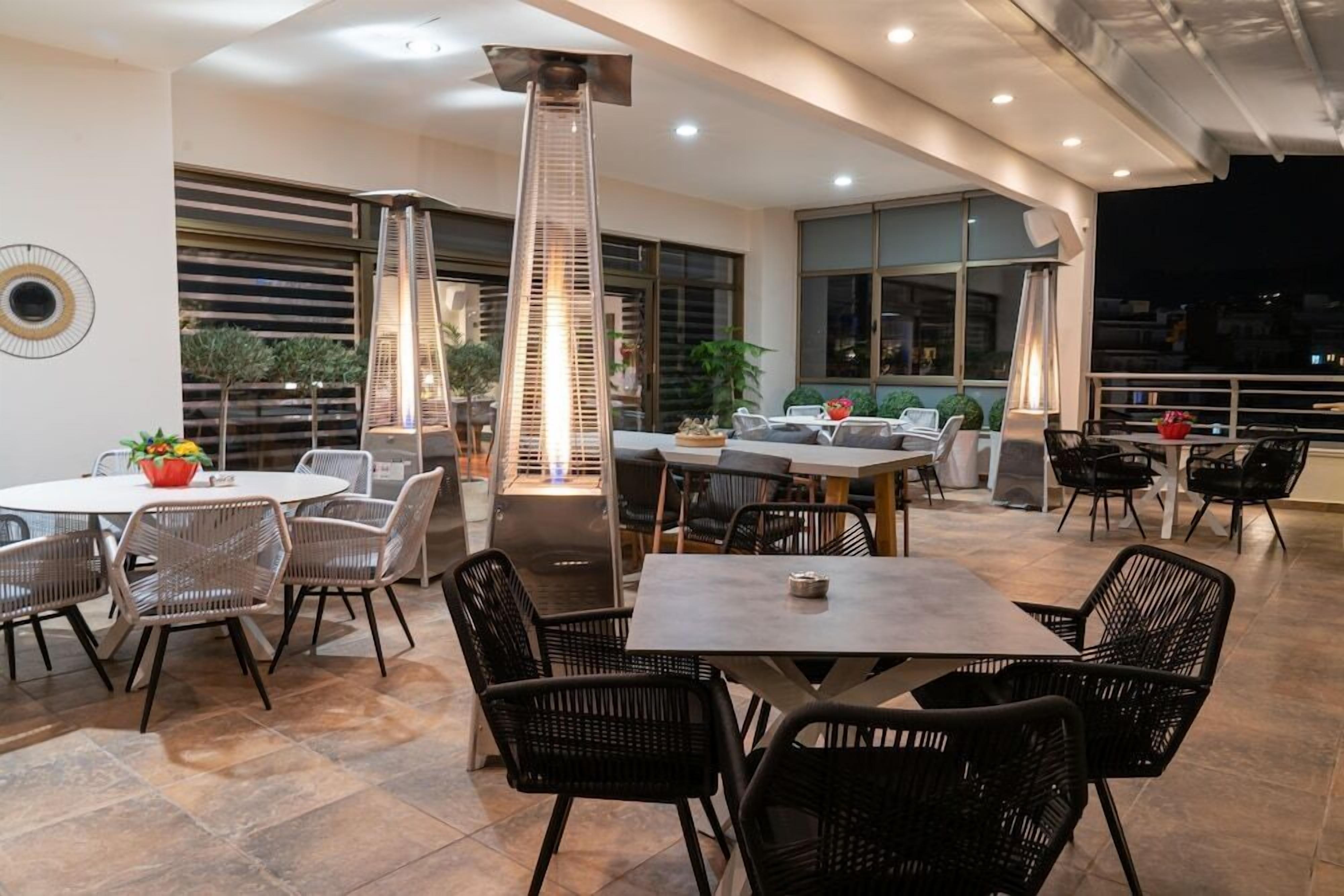 A spacious outdoor dining area with modern furniture, large windows, and a central light fixture.