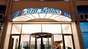 The entrance to a hotel named "Patras Palace" with a glass revolving door and a sign above it. - Patras Palace Hotel (Patras)
