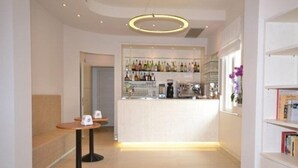 A modern bar area with a counter, shelves of bottles, and a seating area with tables.