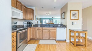 A modern kitchen with wooden cabinets, stainless steel appliances, and a granite countertop.