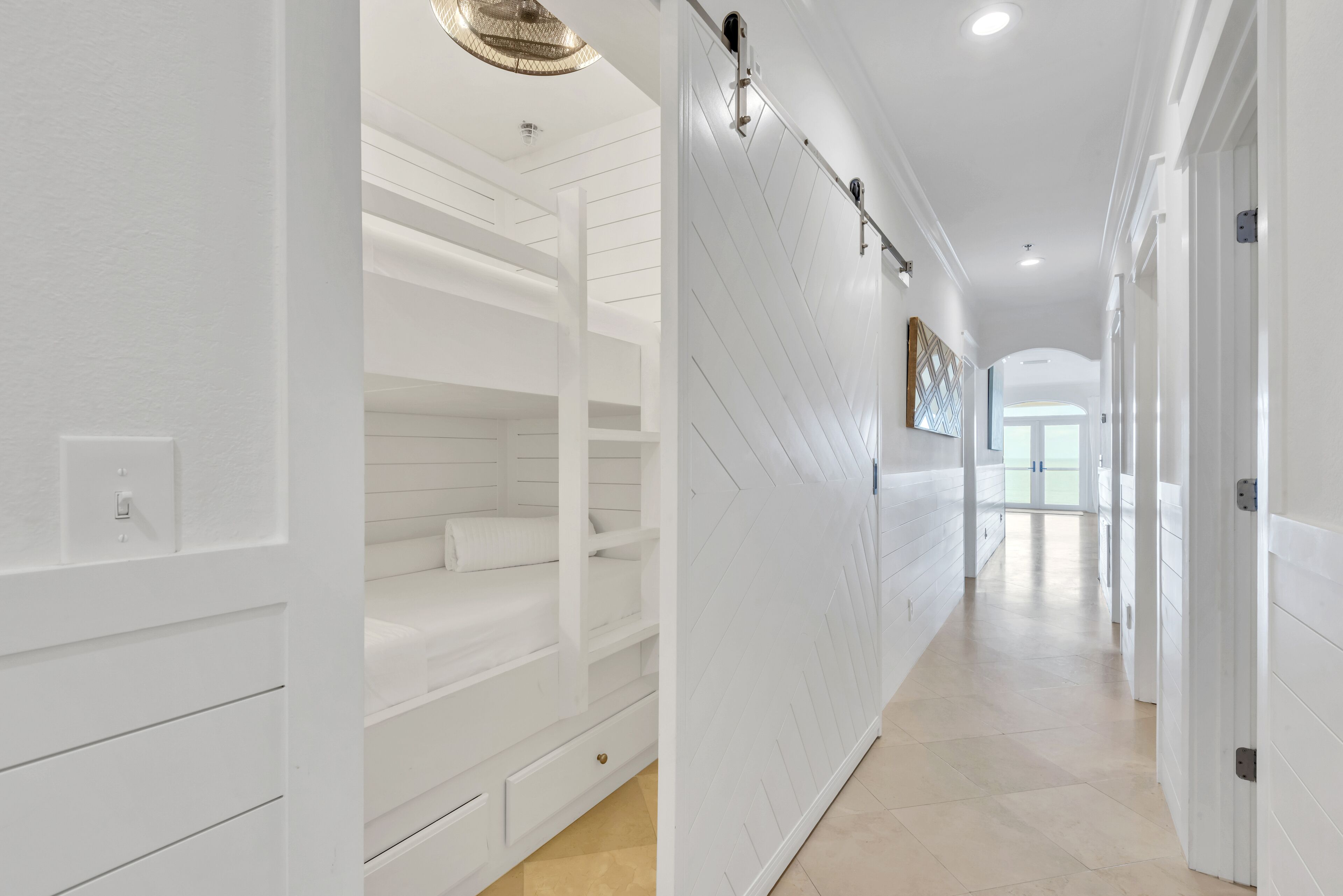 A hallway with white walls, a built-in bench with drawers, and a ceiling light fixture.