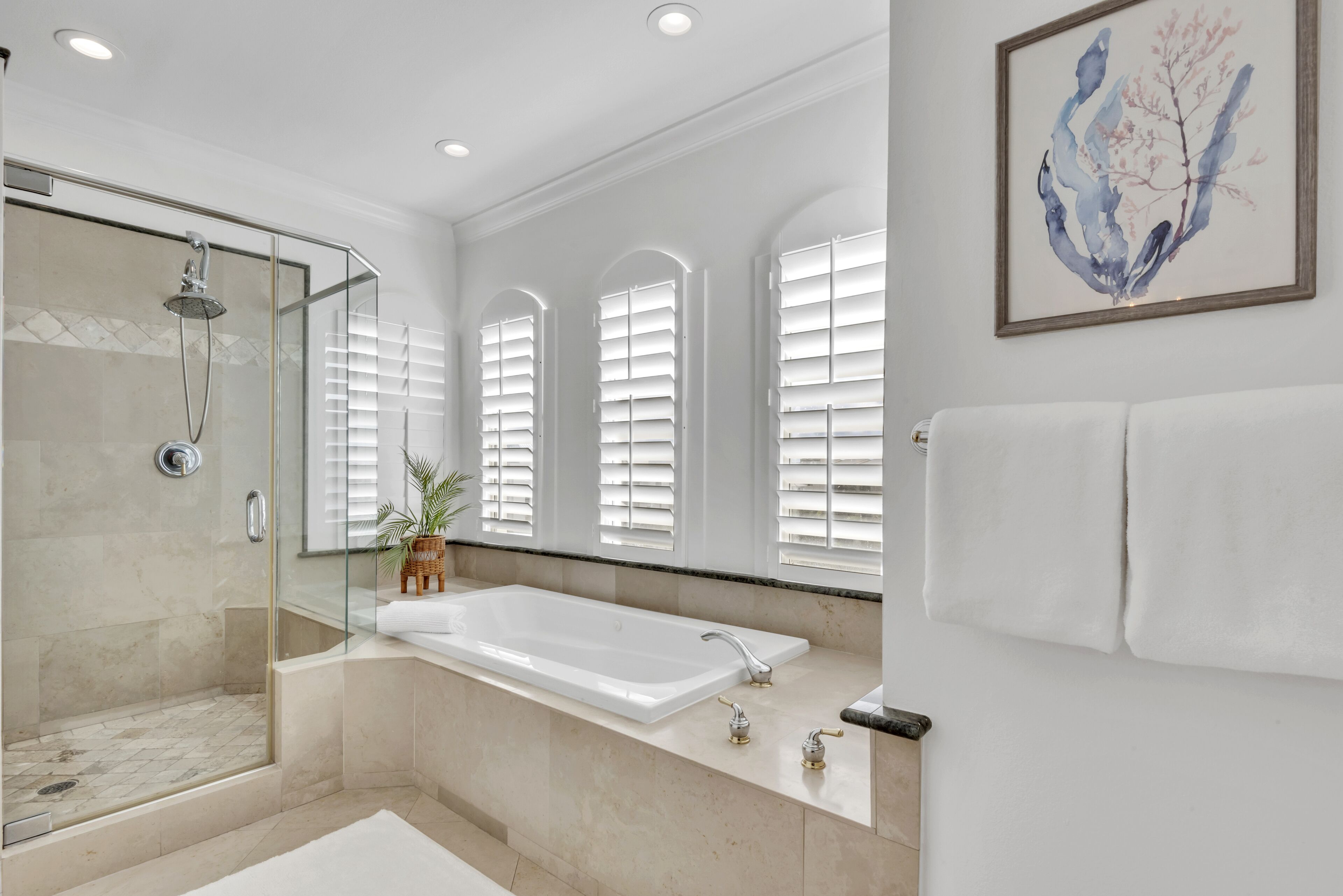 A modern bathroom with a glass-enclosed shower, a large bathtub, and a vanity with a mirror.