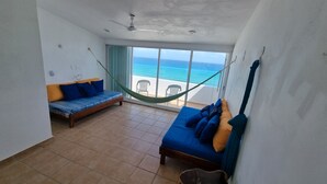 A balcony with a hammock, a sofa, and a view of the ocean. - New Beachfront PH at Brisas By The Spot (Cancun)