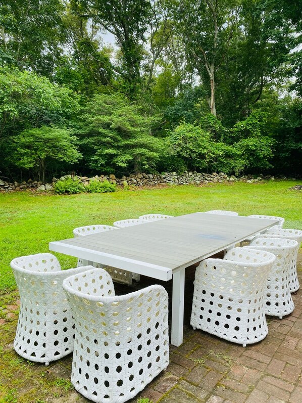 A rectangular outdoor table with a white surface and eight white chairs with circular cutouts. - House on Quicksand Pond...close to beach (Little Compton)