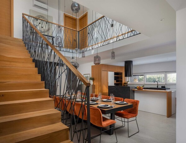 A modern kitchen with a dining area, featuring a staircase with a unique metal railing design.