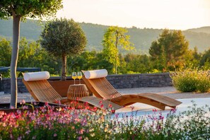A poolside area with lounge chairs and a small table with glasses.