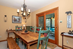A dining area with a wooden table, teal chairs, a chandelier, and a 'WELCOME' sign.
