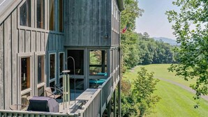 Een houten huis met balkon, met uitzicht op een groen landschap.