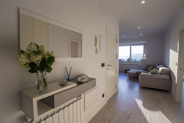 A modern bathroom with a large mirror, a white vanity, and a vase of flowers.