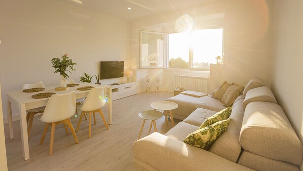 A modern living room with a sofa, dining table, chairs, and a TV. - Balcony at Arousa - Upscale Getaway + Patio (Villagarcía de Arosa)