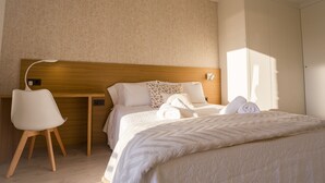 A neatly arranged bedroom with a wooden headboard, a white chair, a bed with white linens, and a large wardrobe. - Balcony at Arousa - Upscale Getaway + Patio (Villagarcía de Arosa)