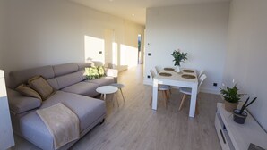 A modern living room with a sofa, a dining table with chairs, and a small side table. - Balcony at Arousa - Upscale Getaway + Patio (Villagarcía de Arosa)