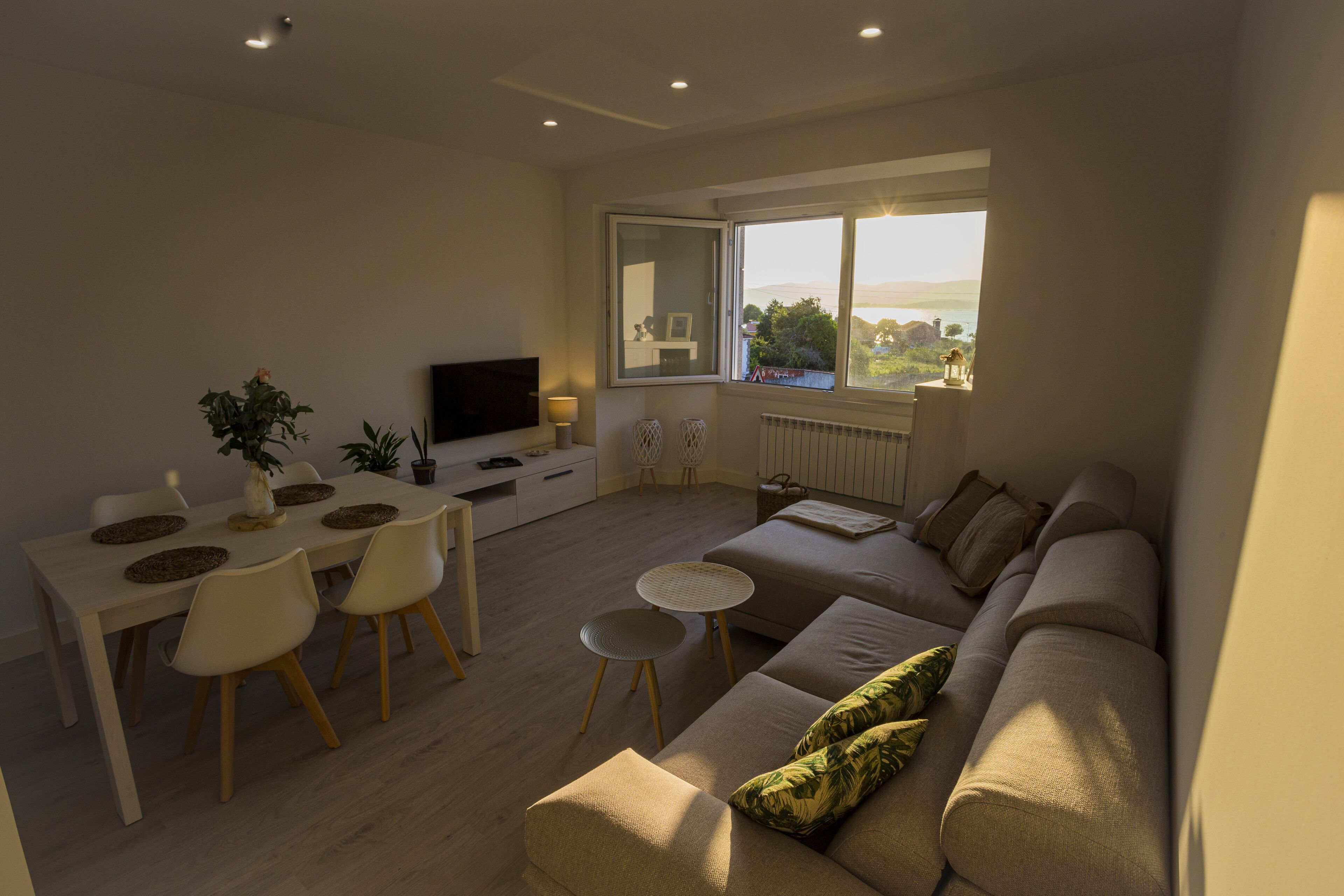 Un salon moderne comprenant un canapé, une table à manger, des chaises et un téléviseur.