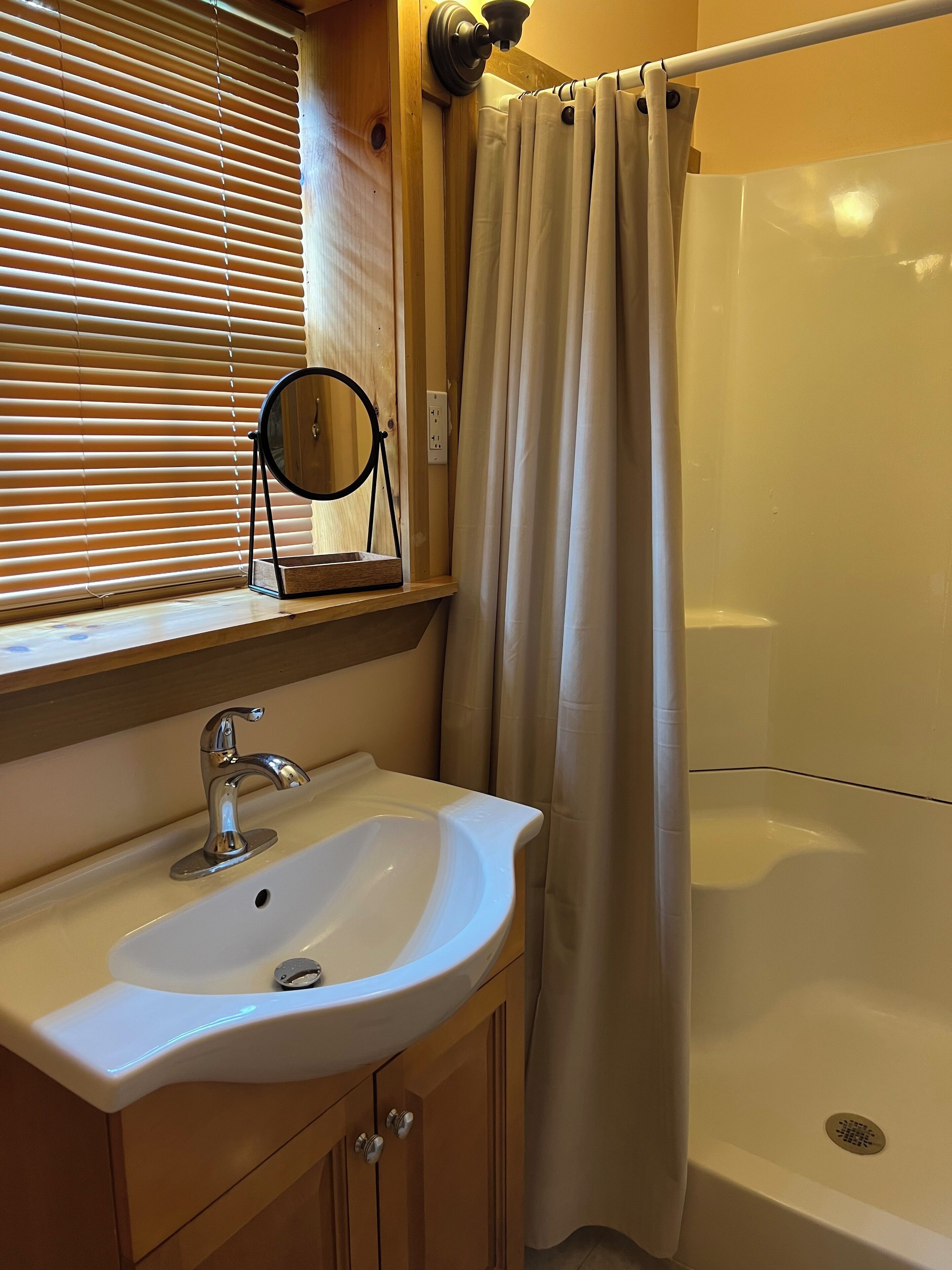 Ein Badezimmer mit Waschbecken, Spiegel und Duschvorhang.