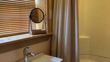Ein Badezimmer mit Waschbecken, Spiegel und Duschvorhang.