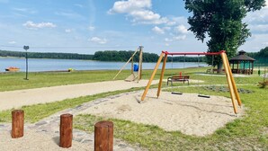 Un parc avec des balançoires, des bancs et un kiosque situé près d’un lac.