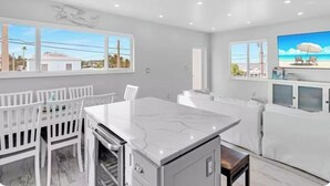 A modern kitchen with white cabinetry, a marble countertop, and a dining area with white chairs. - Amazing Sunsets, Bay Breezes in the beautiful Florida Keys (Key Largo)