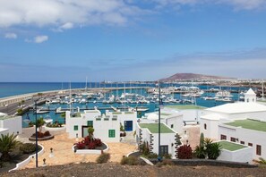 A marina with numerous boats docked, surrounded by white buildings with green accents and a clear view of the sea and distant hills. - Casa Rey si Trova a Playa Blanca a 10 Minuti da Playa Dorada e 15 (lanzarote)