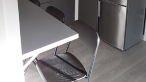 Una cocina compacta con refrigerador de acero inoxidable, un lavamanos y una zona de comedor con mesa y sillas.