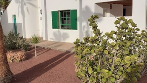 Un edificio moderno con fachada blanca, contraventanas verdes y una ventana pequeña.