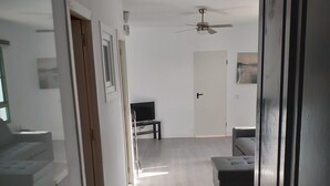 Un pasillo con ventilador de techo, un sofá y una televisión en una sala de estar.