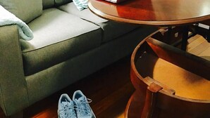 A living room with a grey sofa, a wooden coffee table, and a pair of sneakers on the floor. - 2BR Pet-Friendly Getaway on Ursuline in NOLA (New Orleans)