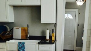 A kitchen with white cabinets, a black countertop, and a dining table with chairs. - 2BR Pet-Friendly Getaway on Ursuline in NOLA (New Orleans)