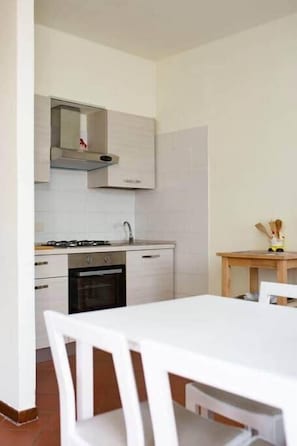 Una cocina moderna con armarios blancos, una estufa a gas y una pequeña mesa de comedor con sillas.