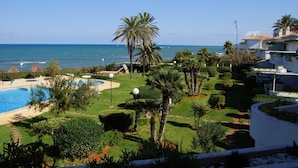 Ein Resort mit Swimmingpool, Palmen und Blick auf den Ozean.